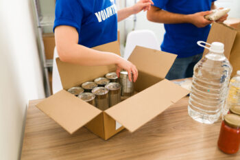Caucasian volunteers receiving donations of canned food for people in need. Young people preparing packages at the donation center