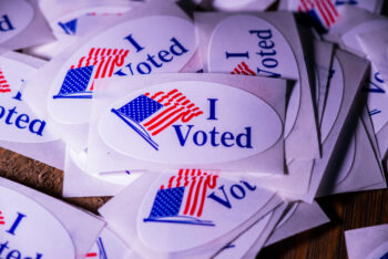 Shiloh, IL--Jul 1, 2020; pile of red white and blue oval stickers with words I Voted and American flag that are presented to people after casting a ballot in a primary or general election.