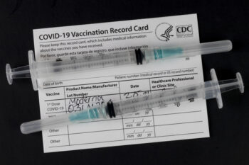 Indianapolis - Circa February 2021: COVID-19 Vaccination Record Card with syringes or hypodermic needles. Vaccination Record Cards will be offered with each vaccination and a reminder for the second dose.